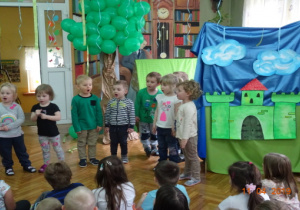 Ekologiczna dekoracja: zielony zamek, chmury, zielone balony oraz dzieci recytujące wierszyk.